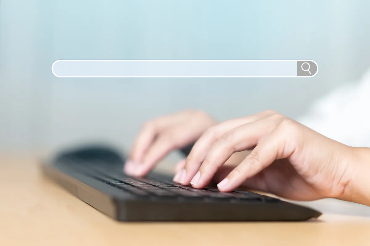 Hands on a keyboard under a search bar